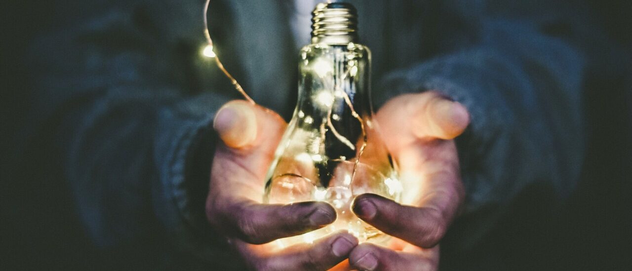 Two hands holding a lightbulb