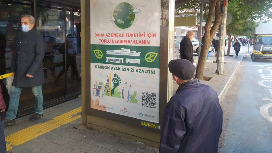 Man looking at poster with environmental message at a bus stop